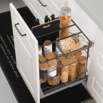 The subject is a white pull-out storage unit in a kitchen. The unit has two metal baskets and one clear basket. The colors are white,
